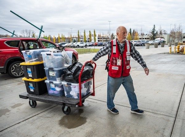 Paul Miller, a Red Cross volunteer from Maine, helps unload shoes donated by a local business for evacuees who arrived without shoes or socks, at the Alaska Airlines Center, in Anchorage, Alaska