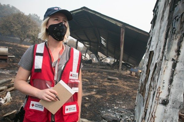 A Red Cross volunteer inspects damage after a wildfire