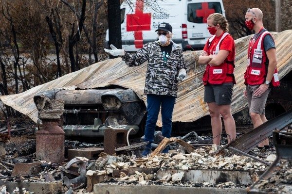 Red Cross volunteers meet with a homeowner after a wildfire