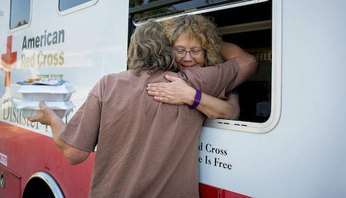 Wildfire survivor David Commerford gets a hug and a hot lunch from Red Cross volunteer Judy Pike.