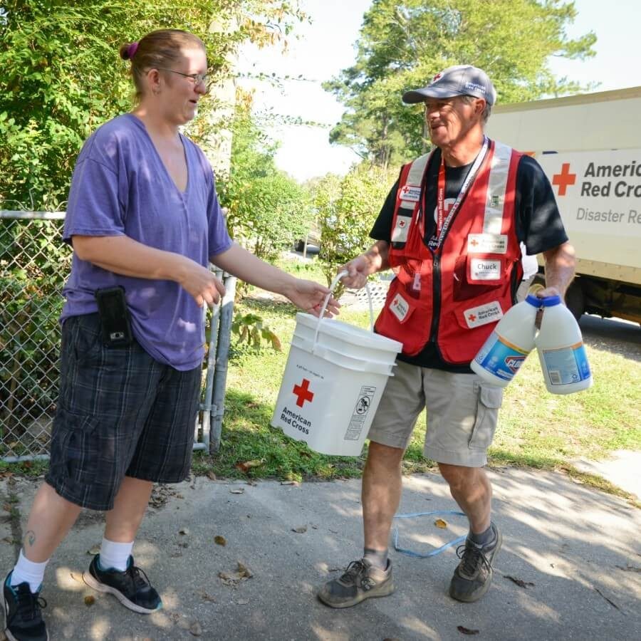 A Red Cross volunteer gives family impacted by hurricane clean up supplies.