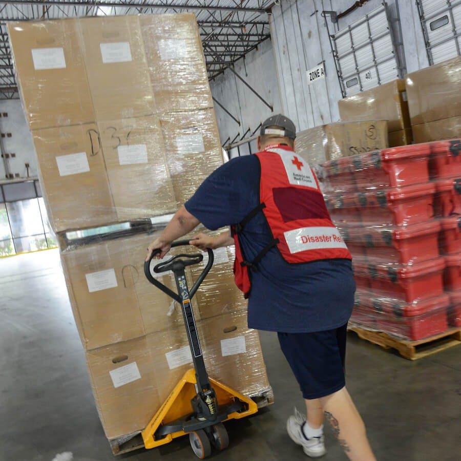 Red Cross volunteer moves a pallet of water.