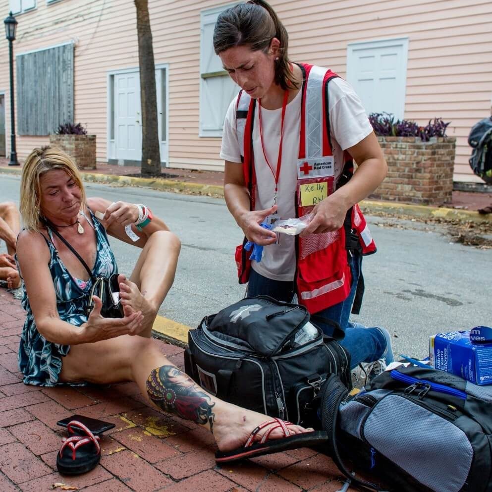 A Red Cross volunteer assisting a woman with medical care.