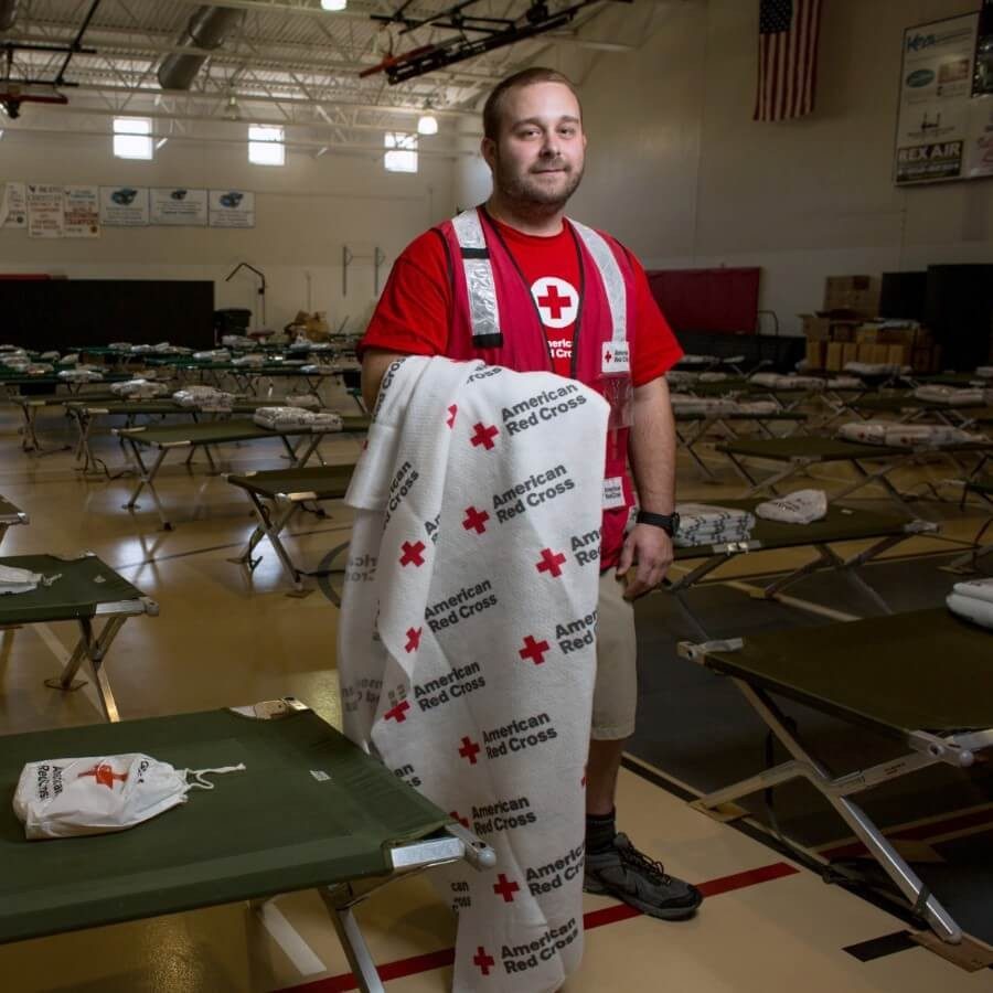 A Red Cross volunteer sets up cots in shelter