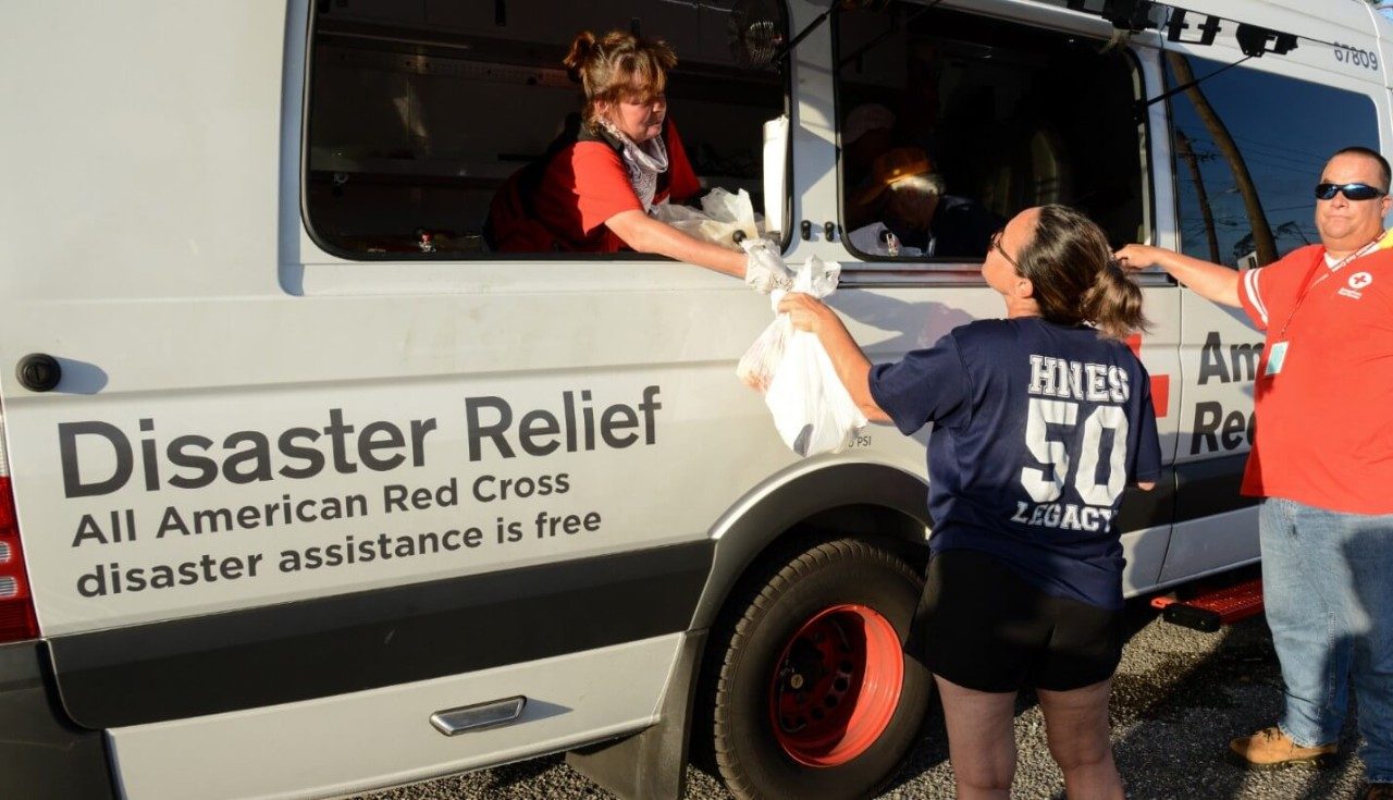 A Red Cross volunteer in a disater relief truck handing out emergency supplies.