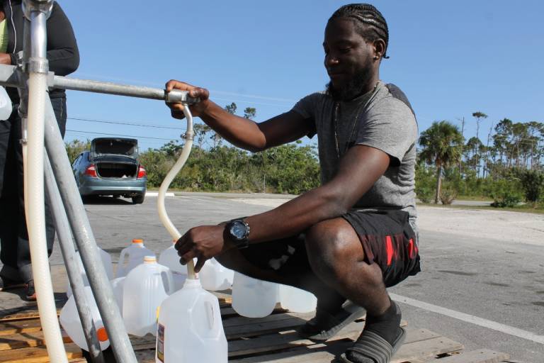 A man filling up water jugs with water from a distribution site.