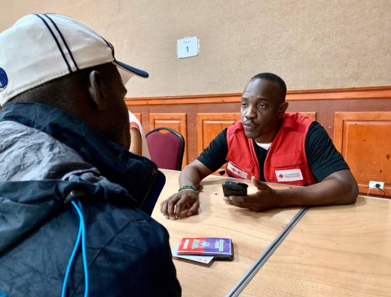 A Red Cross volunteer explains how to use funds for Hurricane Dorian recovery to an evacuee on Nassau.