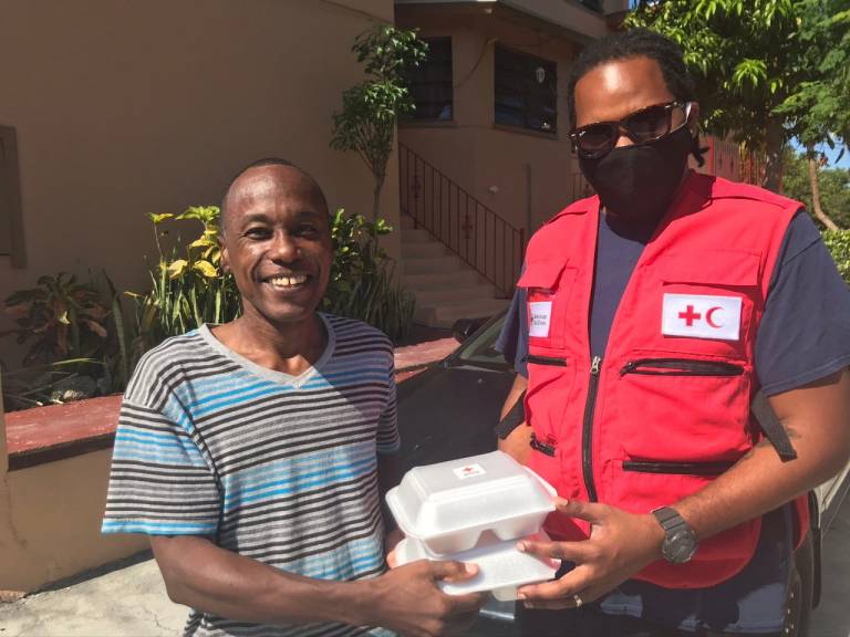 A Red Cross volunteer giving a local resident boxes of food.