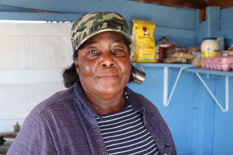 Winifred Mitchell smiling in a home with food on the shelves.