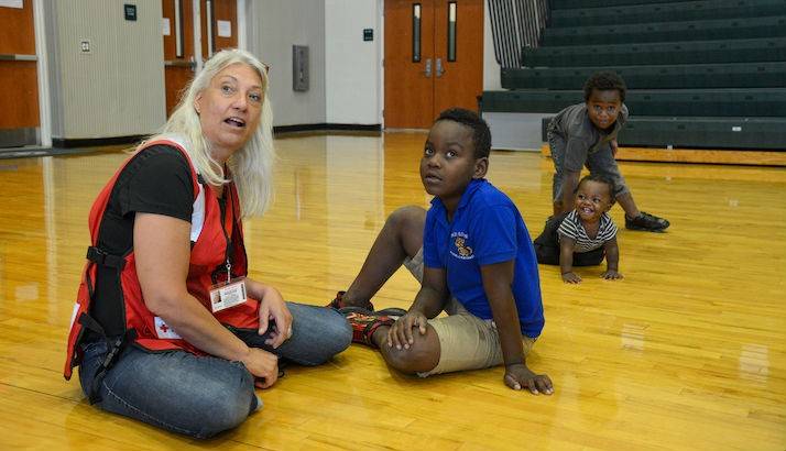 Red Cross worker Michelle Dally plays with 1-year-old Keelen, 6-year-old Victor, and 7-year-old Deshawa at the Red Cross evacuation center.