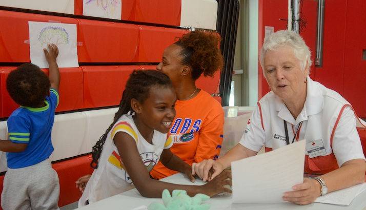 American Red Cross volunteer Lindsay Stroh teaches and sings a song about hurricanes with 7-year-old Tessiyah at the Red Cross evacuation center.
