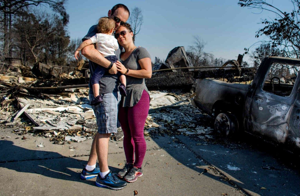 Family hugging near destroyed home