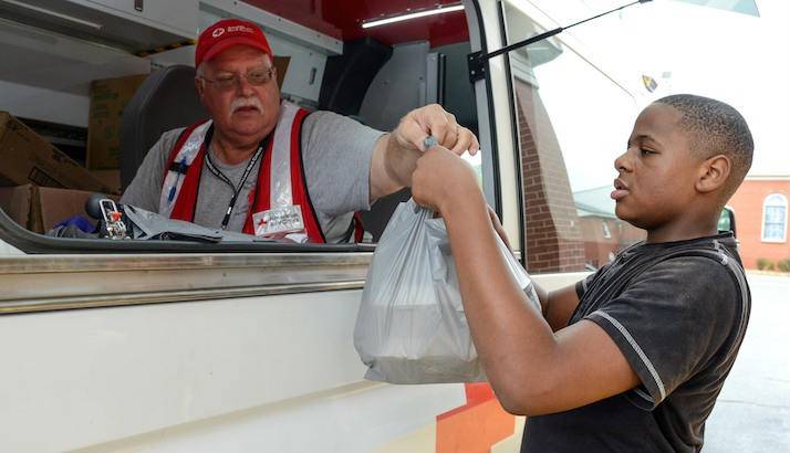 A Red Cross volunteer passing out food to residents.