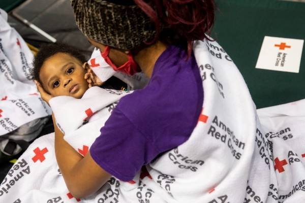 Ednisha, age 14, holds baby brother Ethan as their family waits for Hurricane Ida to pass at a Red Cross evacuation shelter in Baton Rouge, LA.