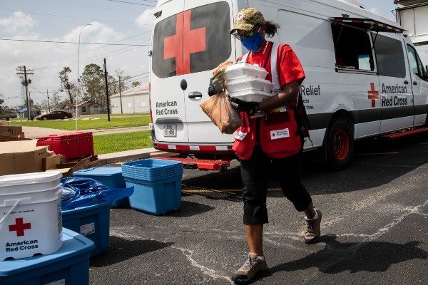 A Red Cross volunteer distributes hot meals to people affected by Hurricane Laura