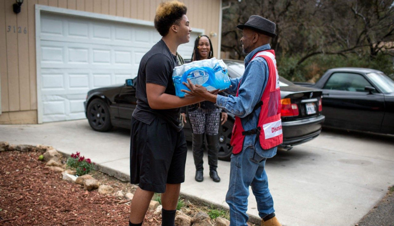 A Red Cross volunteer delivering relief supplies to a man.