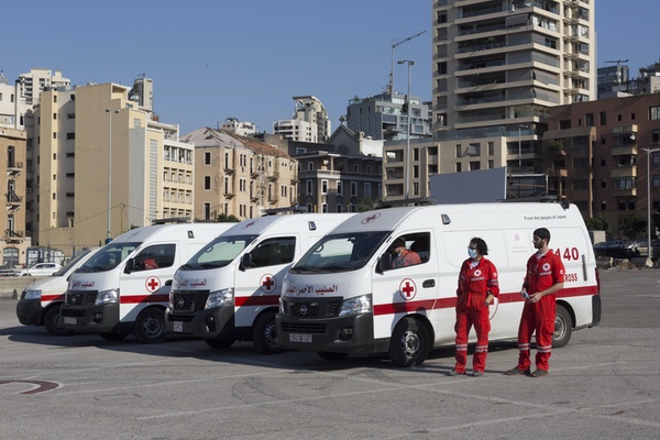 Volunteers with the Lebanese Red Cross stand near trucks, ready to help