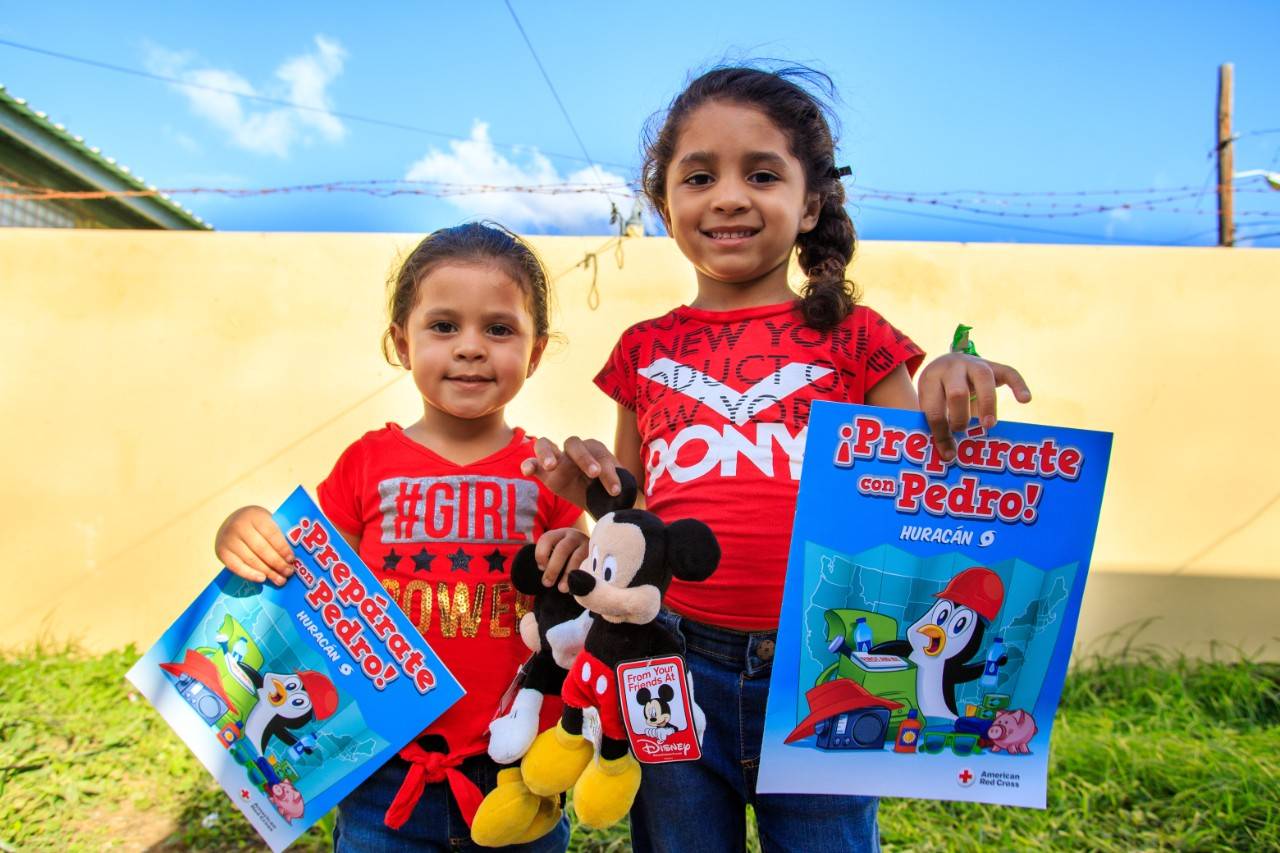 January 10, 2020. Refugio Ramón Baldorioty de Castro, Ponce, Puerto Rico. Sisters Reina Liz standing on the left, and Joslianys, standing on the right, told us how they participated in the Prepare with Pedro workshop and received a Mickey Mouse doll. Photo by Isaac León/American Red Cross