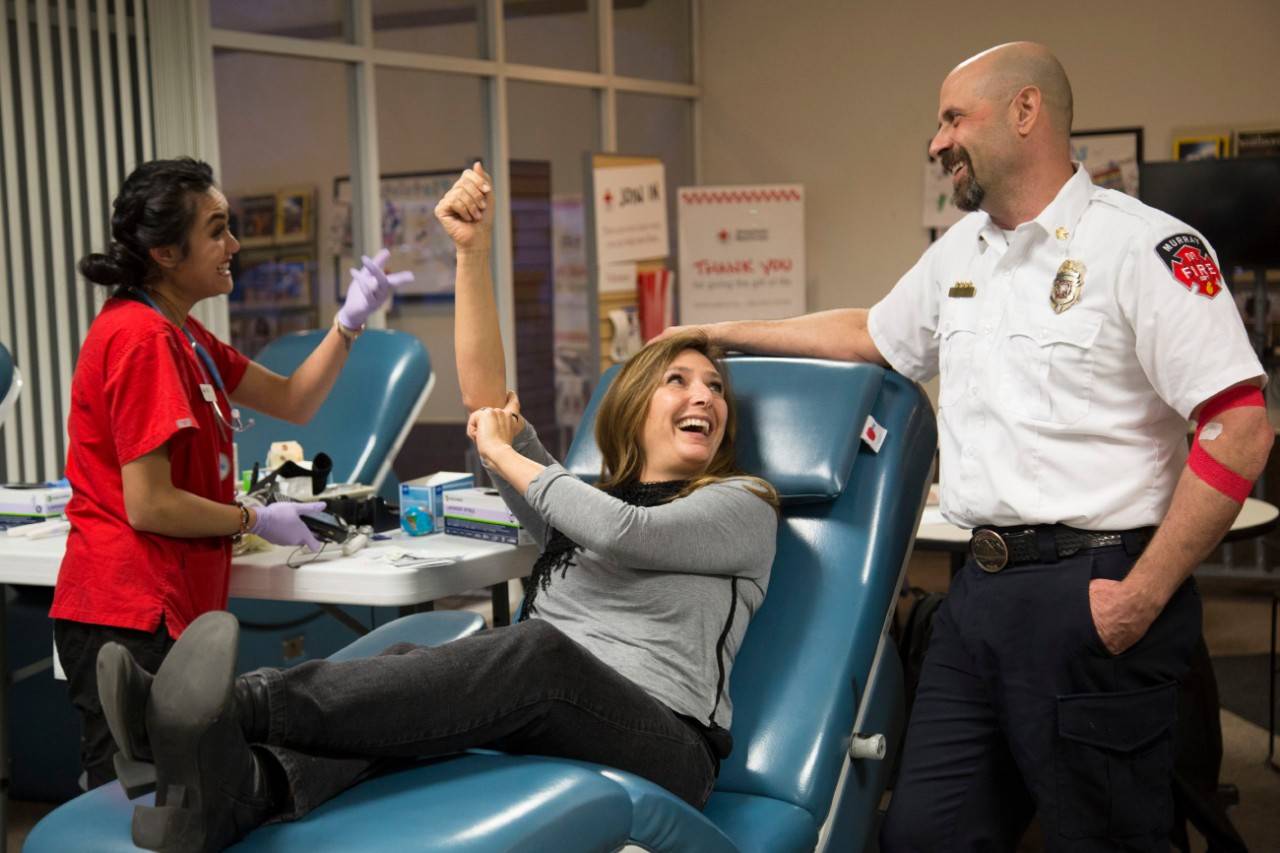 September 18, 2018. Salt Lake Blood Donor Center, Murray, Utah. Whole blood donor Amy Harris shares a post-donation laugh with her husband, Murray Fire Chief Jon Harris, and American Red Cross staff member Deshayla Tran. The Harris family gives blood together often; usually bringing their son, as well. Photo by Amanda Romney/American Red Cross