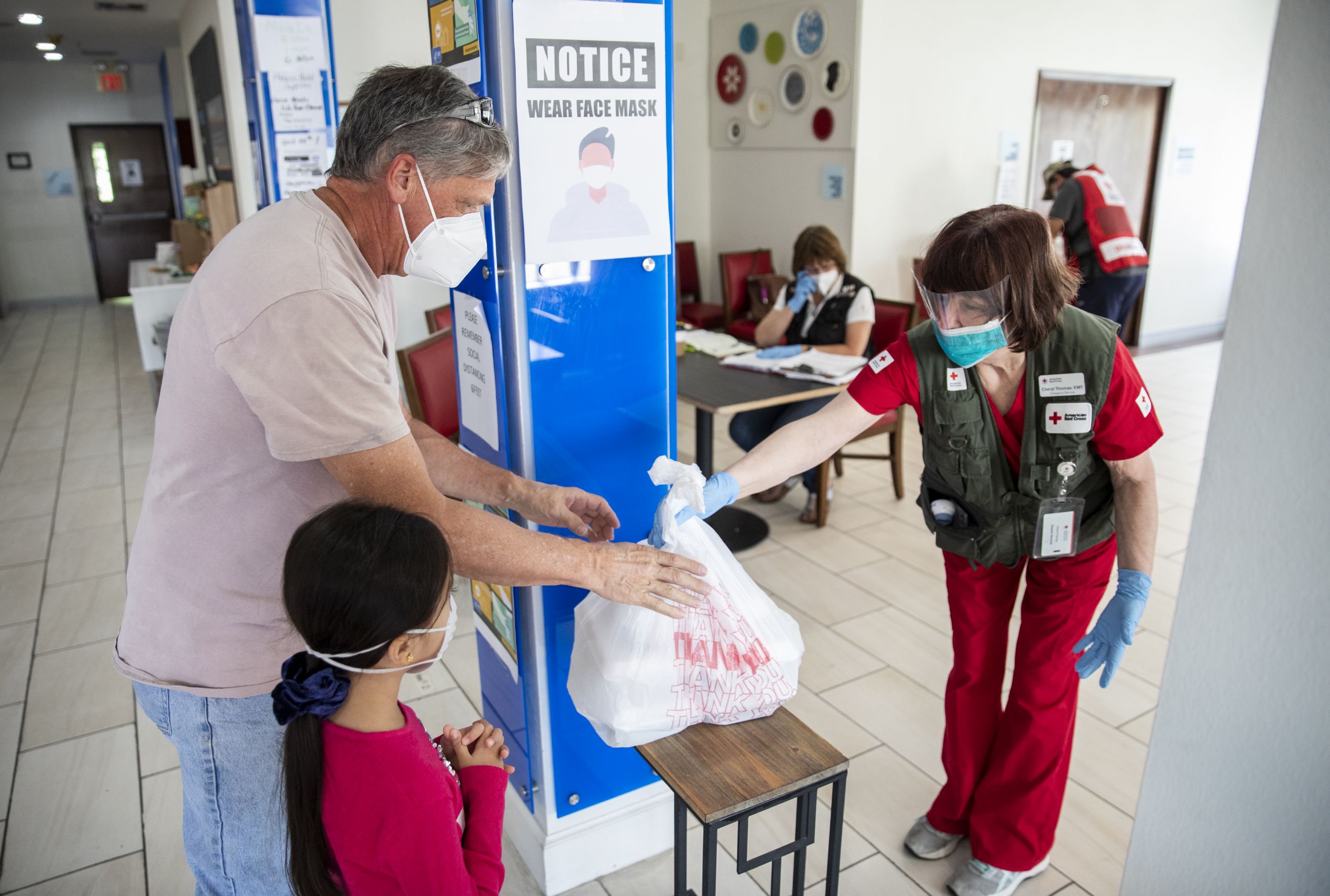 April 26, 2020. Livingston, Texas.
Cheryl Thomas, a nurse for the American Red Cross, hands a meal to Marc Sasso and his daughter Rachel, 6 yrs old, as part of Covid-19 screening protocol at a hotel in Livingston, TX on Sunday, April 26, 2020 where the Red Cross is providing emergency lodging for people whose homes were damaged or destroyed by the powerful tornado that hit Onalaska, TX on April 22. The Red Cross is using a hotel to shelter people, rather than opening traditional style congregate shelters due to the Covid-19 pandemic.
Photo by Scott Dalton/American Red Cross