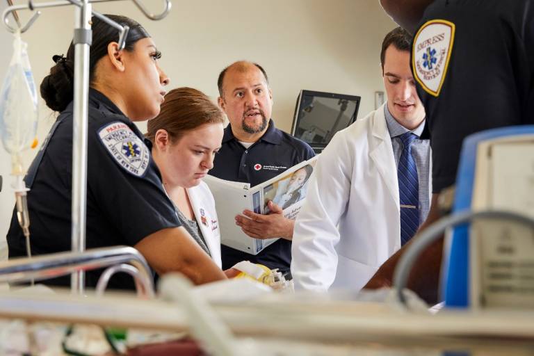 A Red Cross Instructor observes an emergency department team practicing pediatric advanced life support skills.