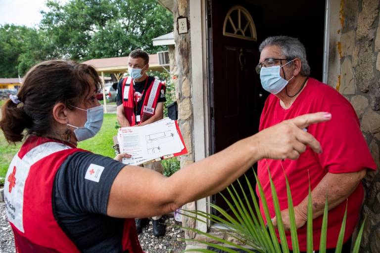 Los voluntarios de la Cruz Roja Americana, Celeste Carrola y Benjamin Quick comparten información con Gerald Davis sobre la seguridad ante incendios domésticos como parte de la visita Activa tu Alarma.