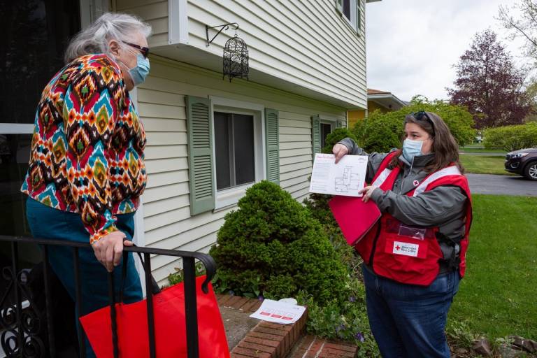 Durante la visita a domicilio Activa tu Alarma, la voluntaria de la Cruz Roja Americana, Melanie Pandich, le muestra un modelo de su plan de escape en caso de incendio doméstico a Mary Kay Smyth, residente de Rochester, Nueva York. 