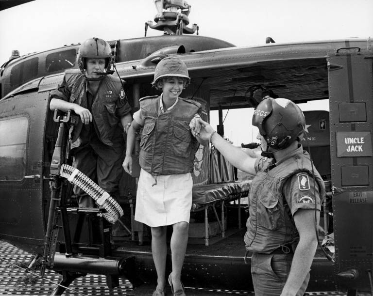 A member of Red Cross staff disembarks from a helicopter after she returns from a visit with troops in a forward area.