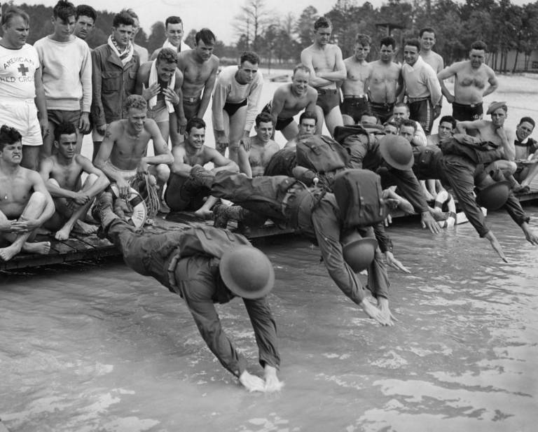 Life Saving instructors hit the water with full uniform and equipment, minus guns, for a practice swim. 