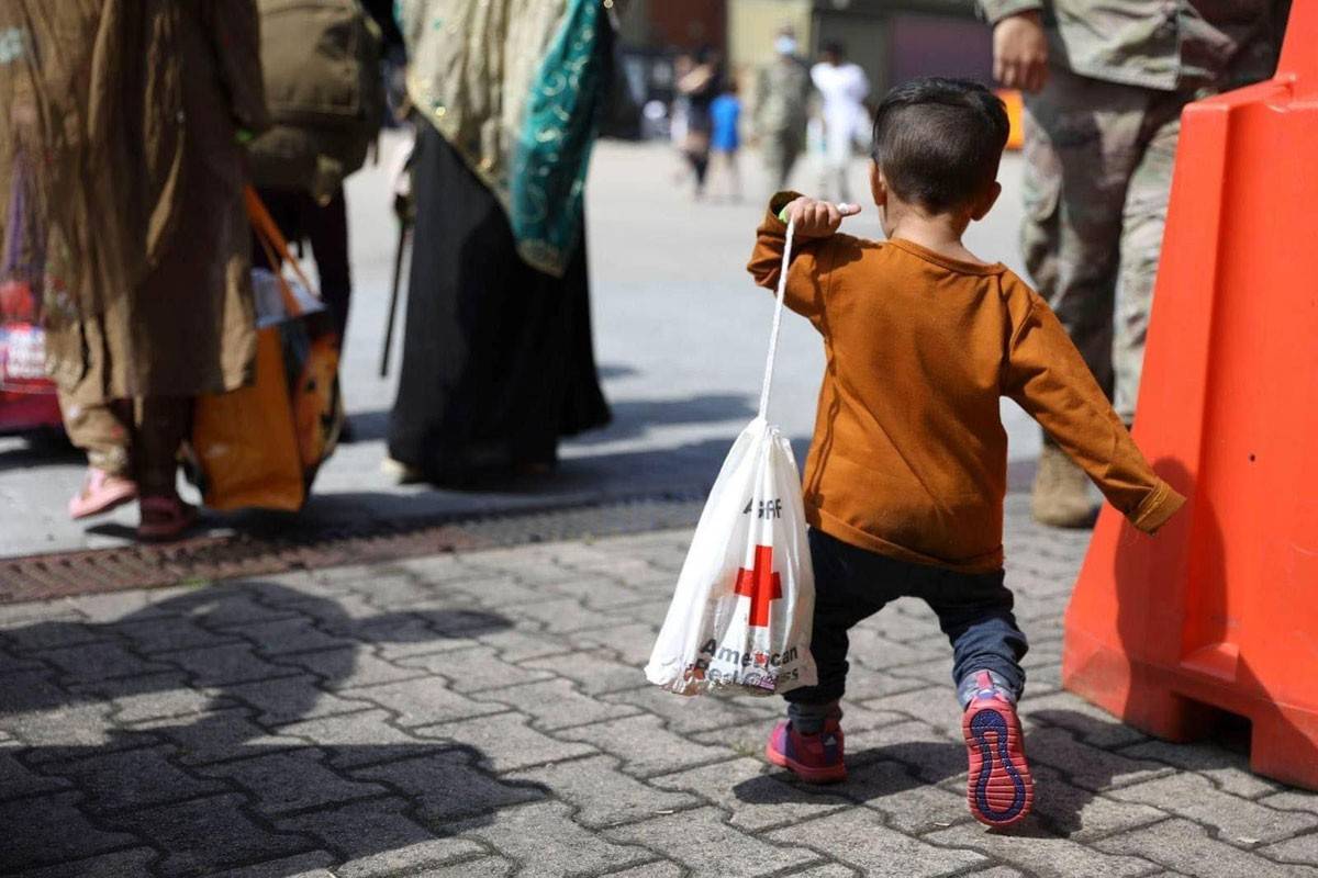 Young Afghan evacuee totes his American Red Cross comfort kit 