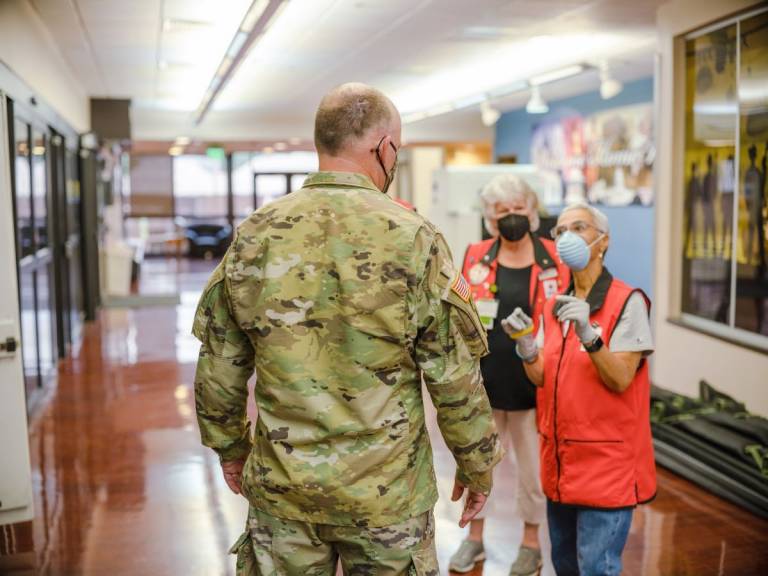 Las voluntarias de la Cruz Roja Deborah Trimiar y Carol Kern hablan con un miembro del servicio en el sistema de estadificación de pacientes en ruta en la base conjunta Andrews en Maryland. 