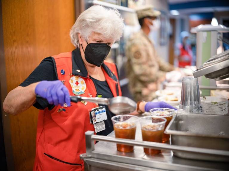 La Cruz Roja Carol Kern sirve comida a los soldados en el Sistema de Estadificación de Pacientes en Ruta en la Base Conjunta Andrews en Maryland.