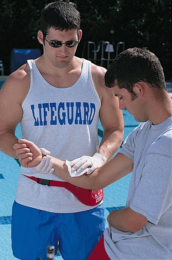 lifeguard assists with first aid near pool