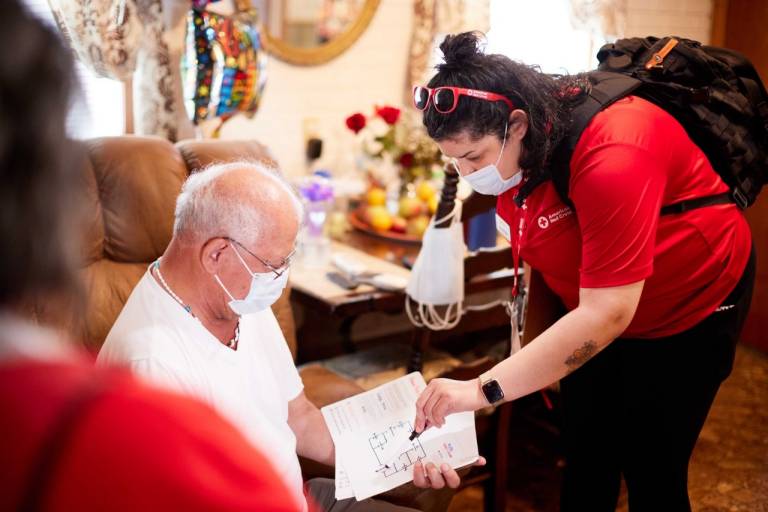 Un voluntario de la Cruz Roja ayuda a un residente a desarrollar su estrategia de evacuación en caso de incendio