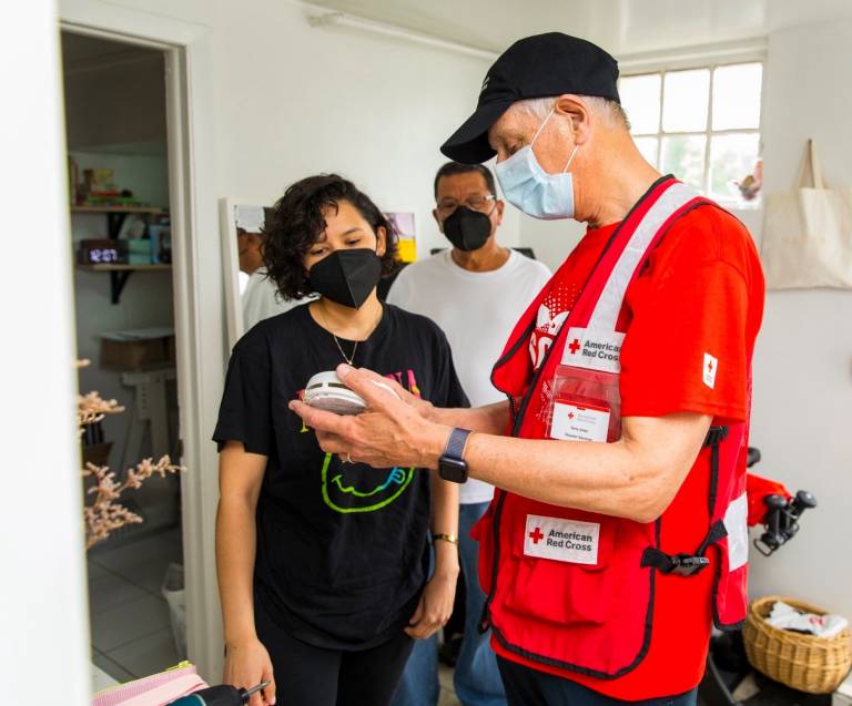 Una voluntaria de la Cruz Roja muestra una alarma de humo a una residente