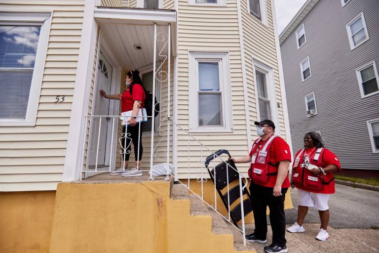 Tres voluntarios de la Cruz Roja tocan la puerta de una casa.