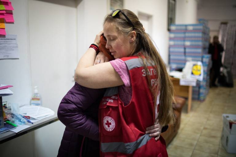 red cross volunteer hugging Ukrainian woman