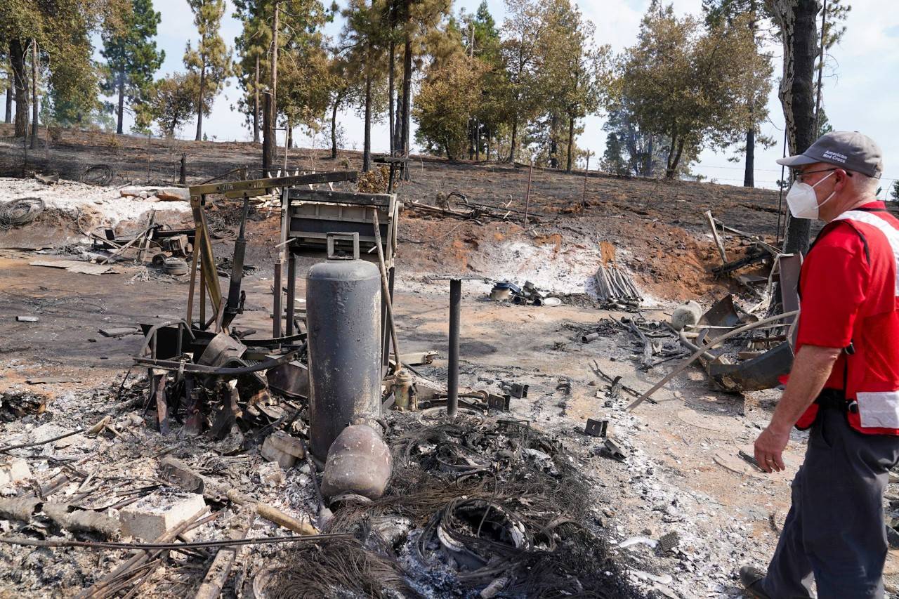July 27, 2022. Mariposa, California. 
Volunteer Dave Wagner surveys the Jerseydale neighborhood near Yosemite National Park after it was ravaged by the fast-moving Oak Fire. Residents evacuated from this area received refuge and care at the Red Cross shelter in Mariposa. The Red Cross will continue to assist with the recovery of everyone affected by this devastating wildfire, connecting them with government and community partners to help get the emotional and financial assistance they need. Photo by Tracy Sebastian/American Red Cross