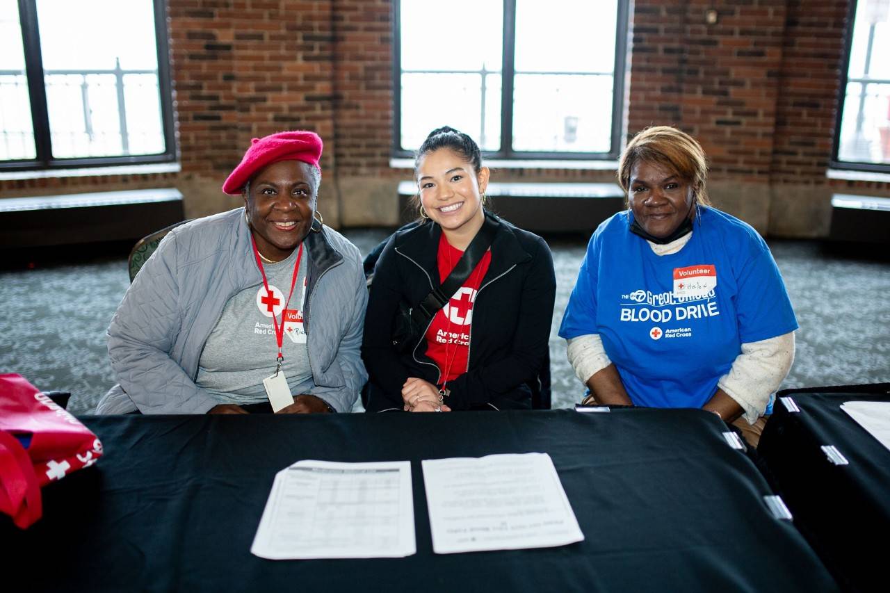 3 Red Cross volunteers sitting at a table talking