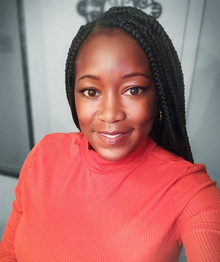 phot of Erica, a black woman with long braids and wearing a red shirt