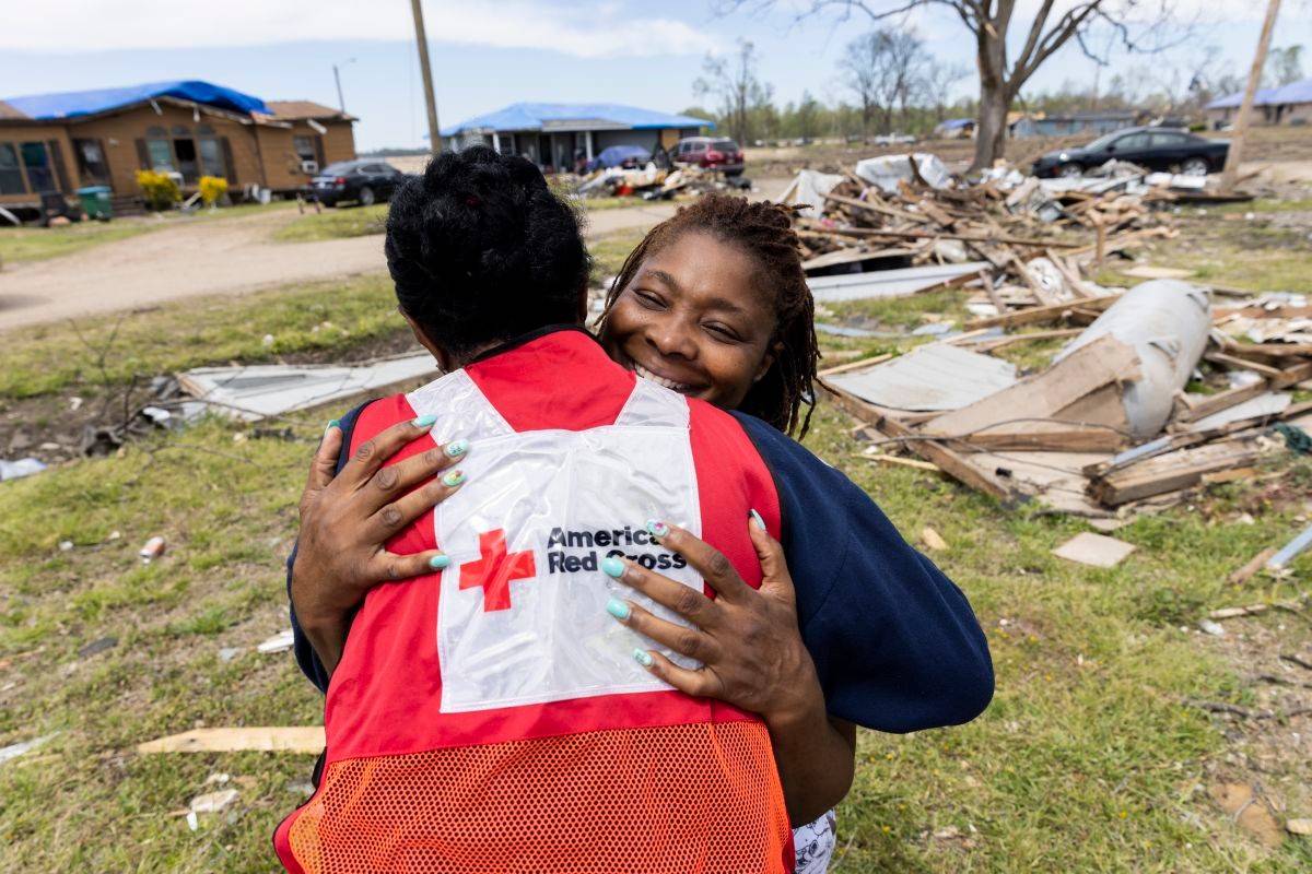 Woman hugs Red Cross volunteer after her house was destroyed