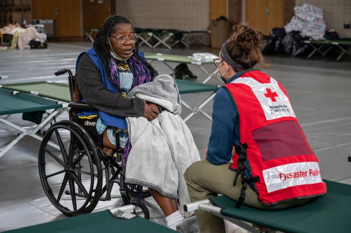 woman in wheelchair is helped by a red cross volunteer