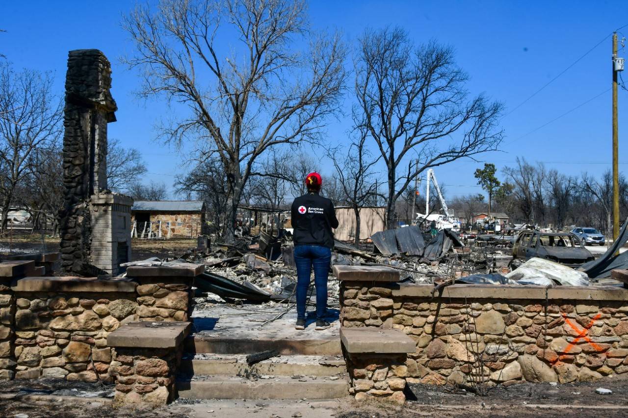 March 19, 2022. Eastland, Texas. An American Red Cross staff member examines the charred remains of a house, destroyed by the eastland Complex wildfires. In total, the fires burned over 54,500 acres and destroyed multiple homes and structures.  Photo by Mark Bishop/American Red Cross