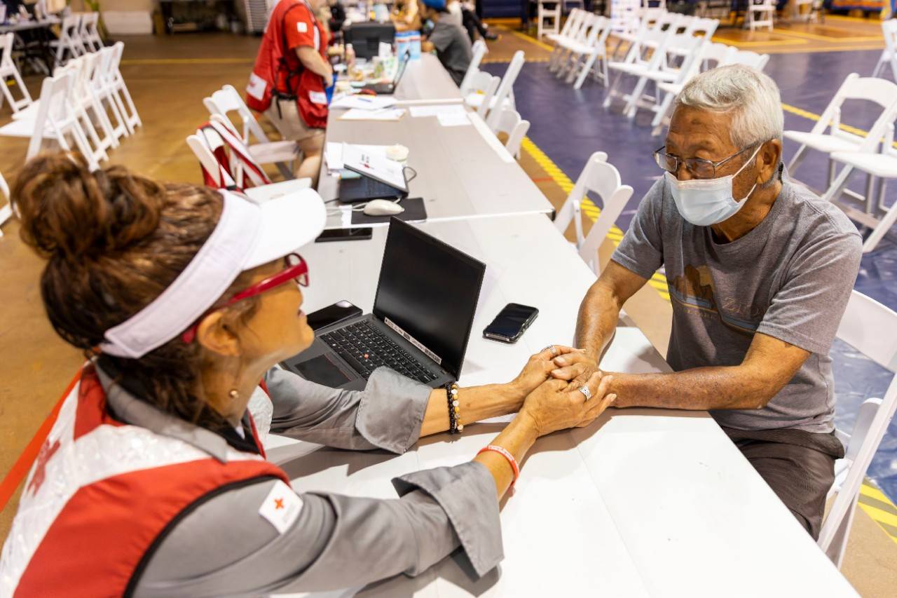 A Red Cross volunteer comforts a man at a shelter