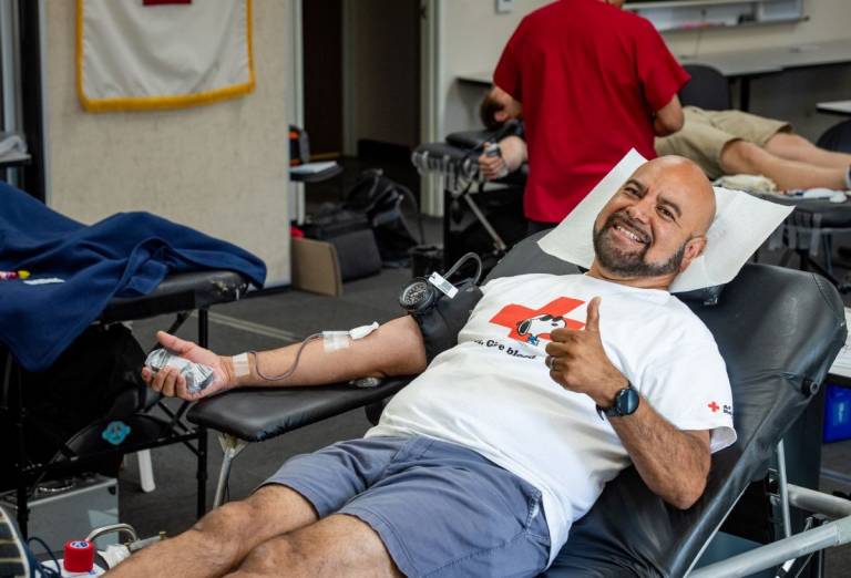 man on donor bed chats with Red Cross technician.
