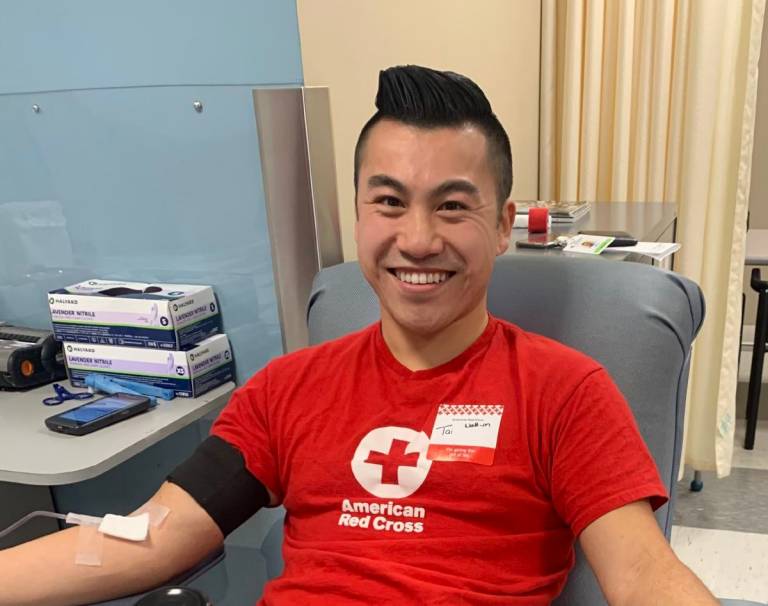 Young man in Red Cross tee shirt with bandaged arm up in the air