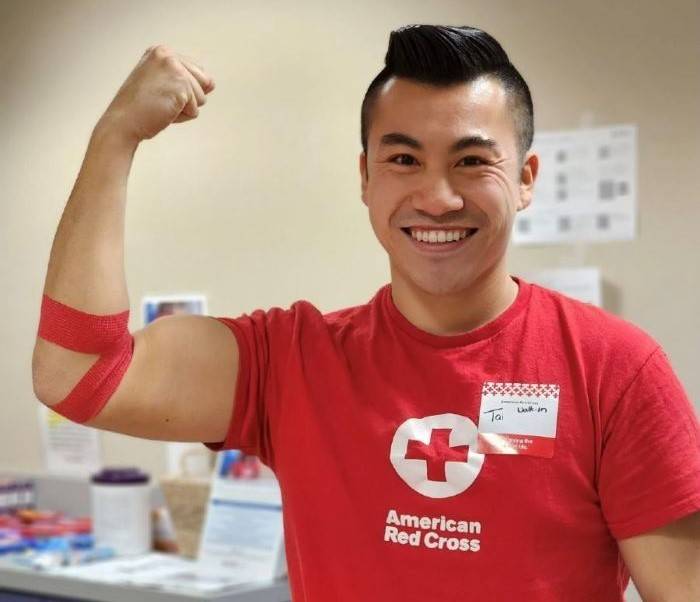 Joven con camiseta de la Cruz Roja y brazo vendado en el aire