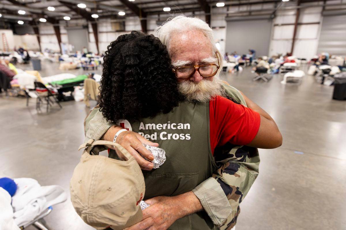 October 10, 2024. Fletcher, North Carolina. 
American Red Cross worker Terry Stigdon embraces Fletcher shelter resident Nathan Garrison. Nathan was one of the many veterans staying in this shelter following the destruction of Hurricane Helene. Since Hurricane Helene wreaked havoc on Western North Carolina, the Red Cross has been working tirelessly to provide shelter, food, water, relief supplies and comfort to those coping with the unimaginable destruction left behind by Hurricane Helene. Hundreds of Red Crossers and our partners have provided meals, snacks and relief items like cleaning and hygiene items for thousands of families affected by Helene.
Photo by Scott Dalton/American Red Cross

