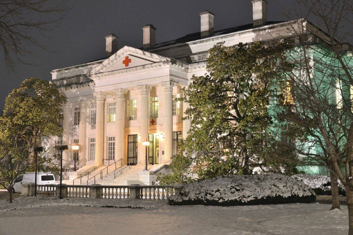 Red Cross 17th Street Building at night, lit up, with snow on the lawn