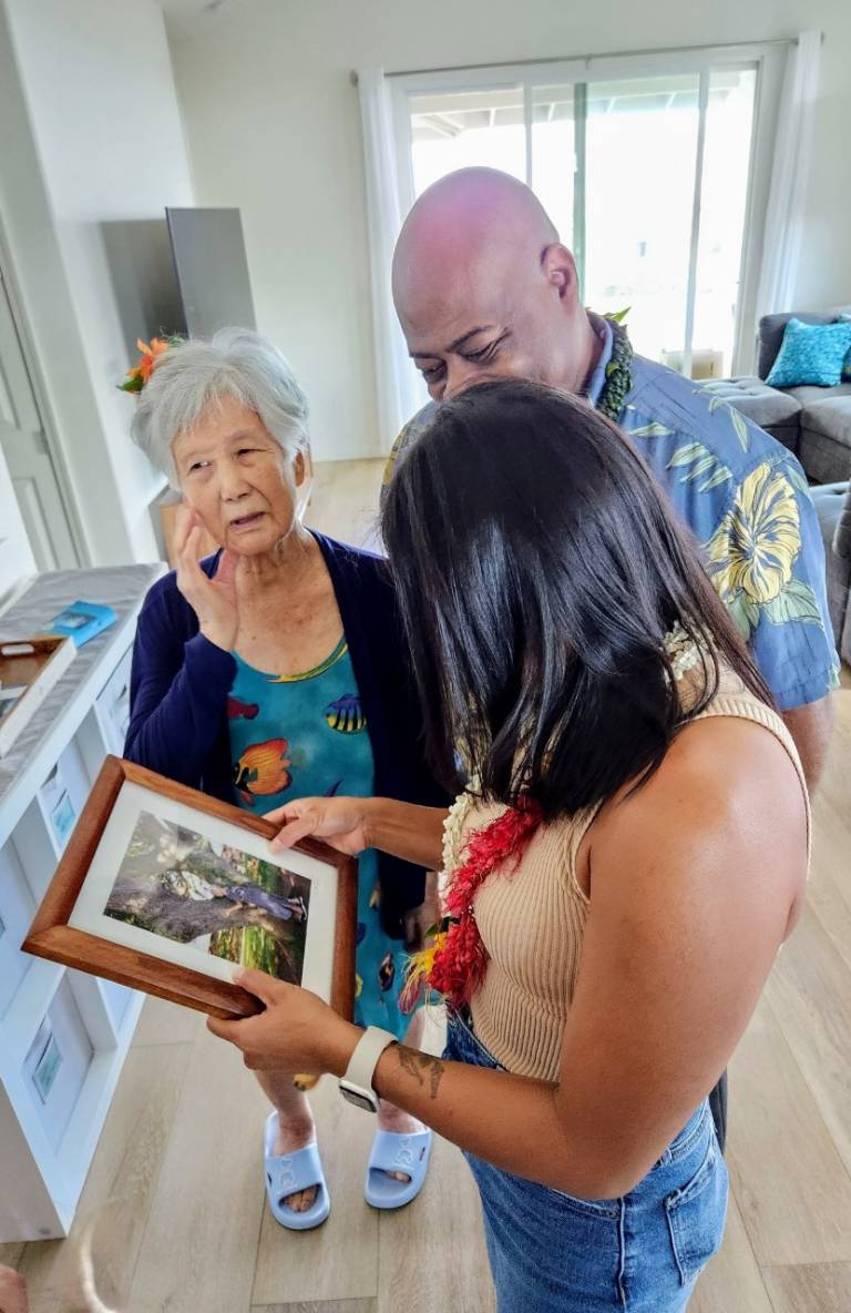 two women and a man look at framed picture